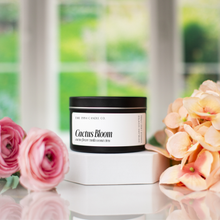 Load image into Gallery viewer, Matte Black 6oz Candle tin labeled 'Cactus Bloom' with flowers in the foreground